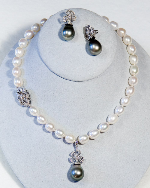 10mm white cultured freshwater pearls  and 15mm black tahitian pearls with 14k white gold filigree and diamond clasp and pendent/earring enhancements.  $3300
